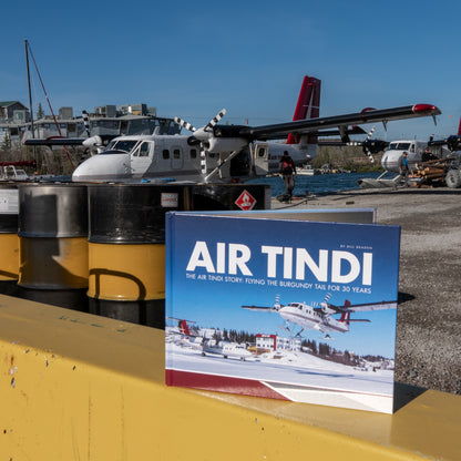 Air Tindi 30th anniversary story book displayed in front of a Twin Otter aircraft in Yellowknife, Northwest Territories.