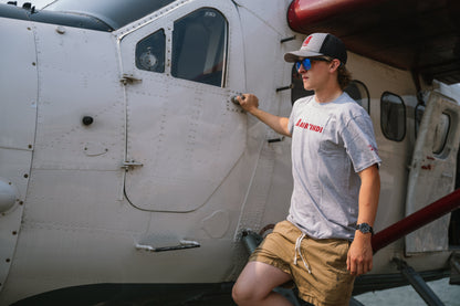 Model wearing an Air Tindi Active Unisex T-Shirt by a floatplane