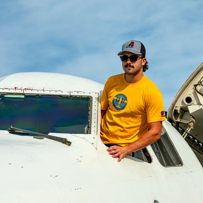 Model wearing the Limited Edition de Havilland Heritage Tee, standing in an aircraft cockpit