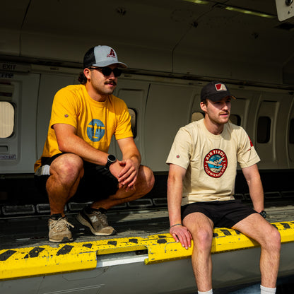 Model wearing the Limited Edition de Havilland Heritage Tee seated inside an aircraft beside a model wearing the Classic Dash 7 Tee