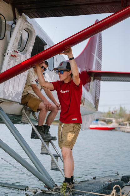Model wearing an Air Tindi Legacy T-Shirt in mens by a floatplane