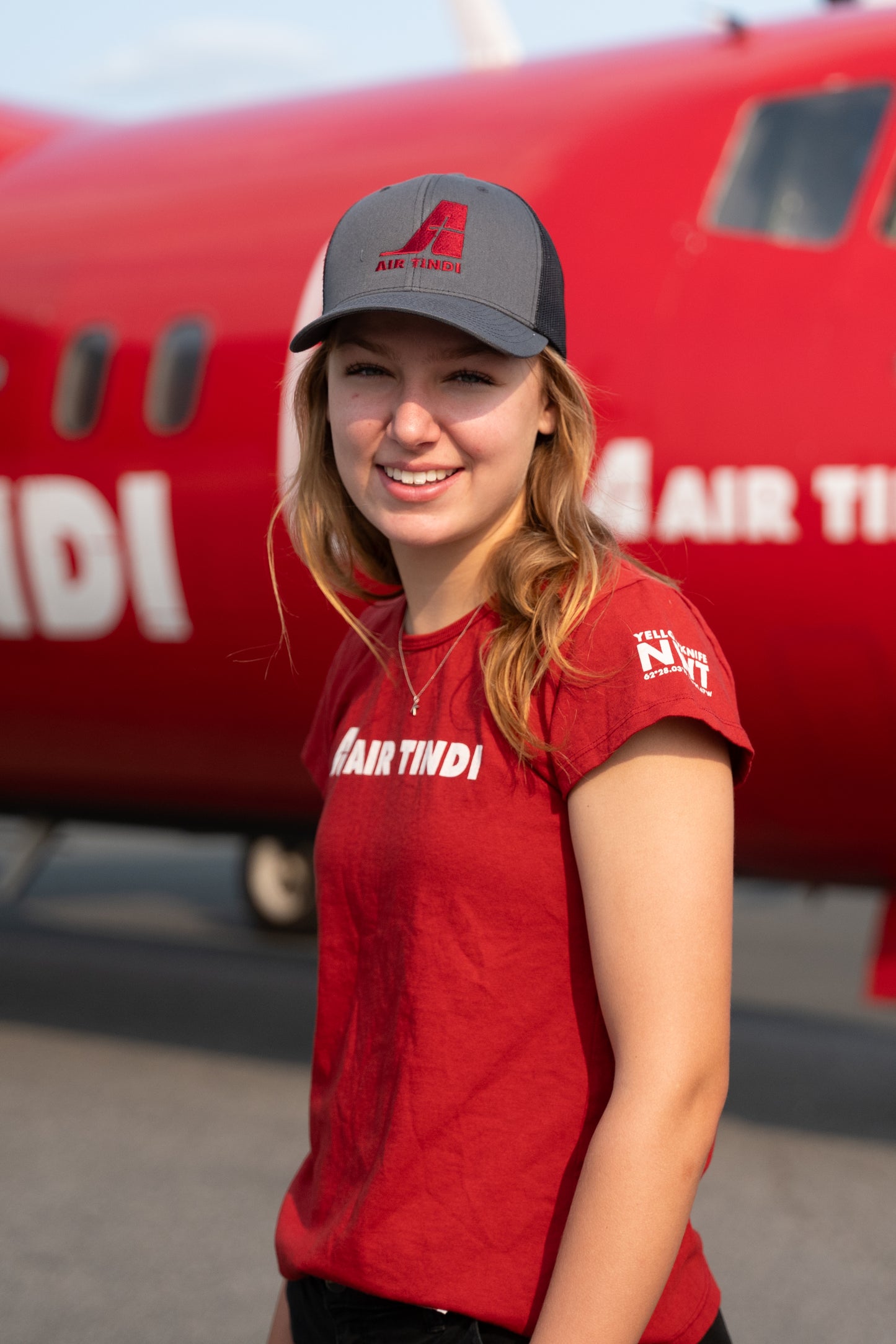 Model wearing an Air Tindi Legacy T-Shirt in womens, and Essential Trucker Cap