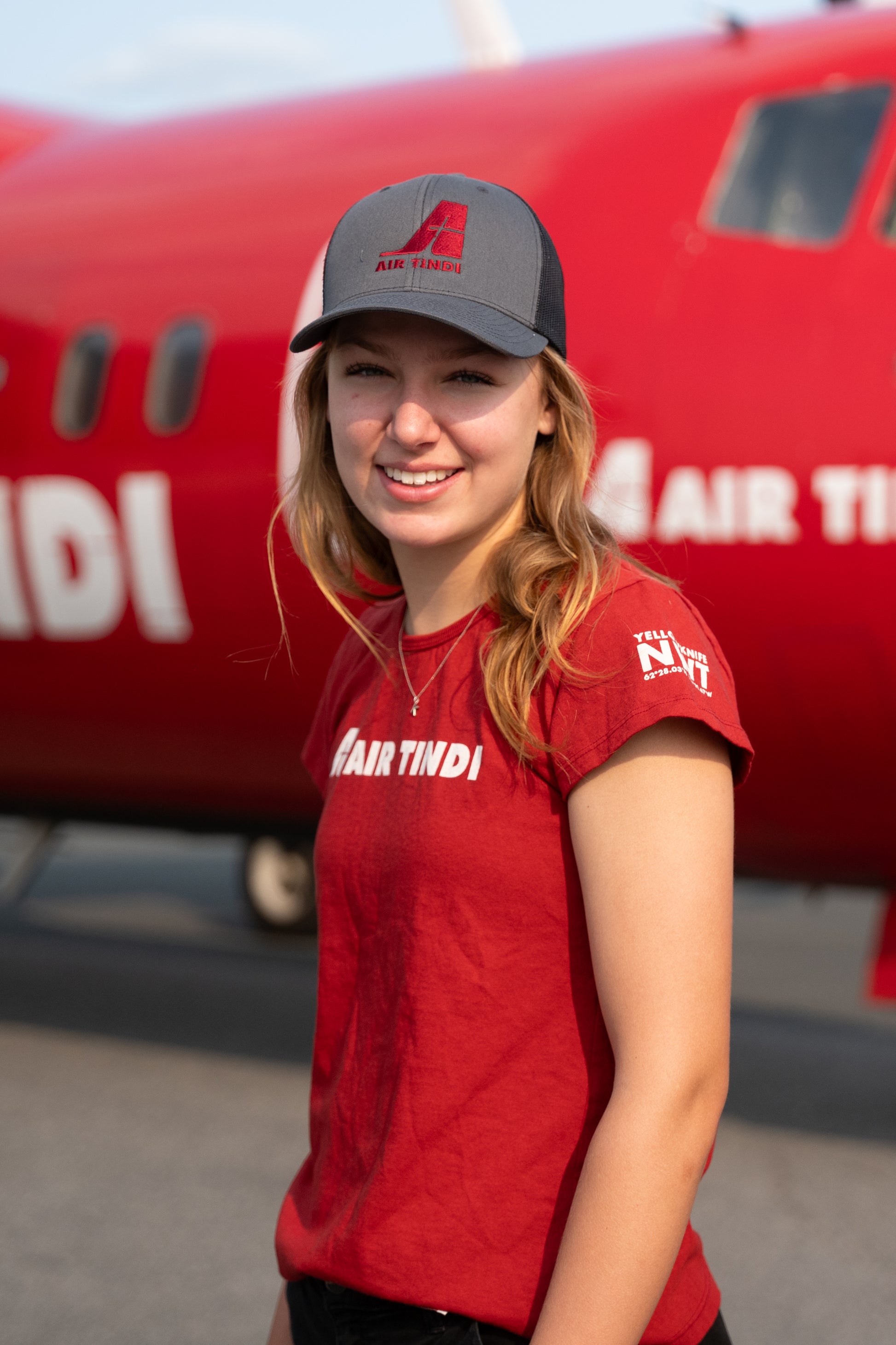 Model wearing an Air Tindi Legacy T-Shirt in womens, and Essential Trucker Cap