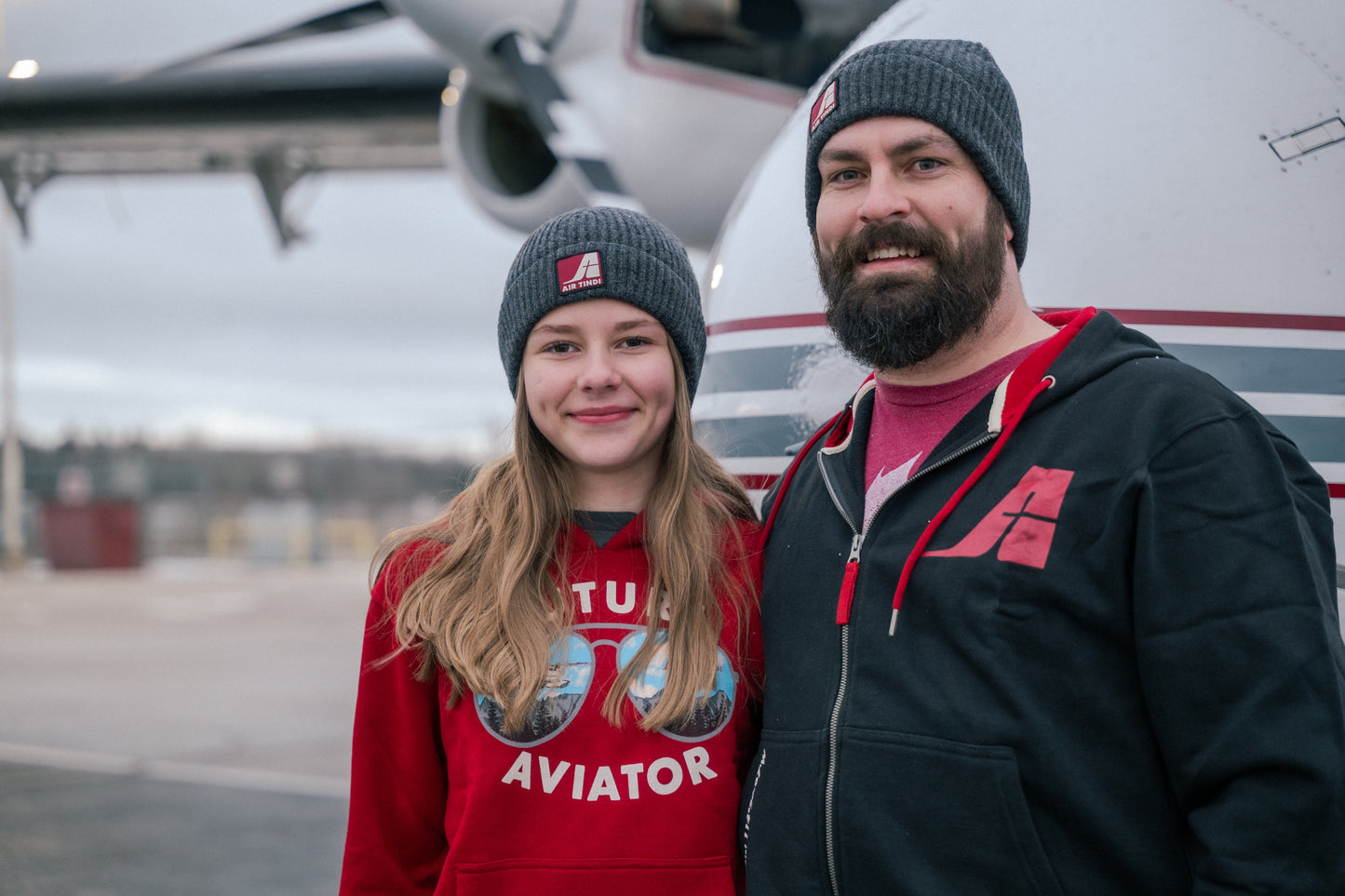 Model wearing an Air Tindi Signature Full Zip Unisex Hoodie, alongside another model wearing a Future Aviator Youth Hoodie