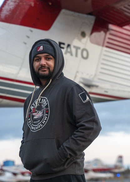 Model wearing an Air Tindi Twin Otter Unisex Hoodie in front of a plane