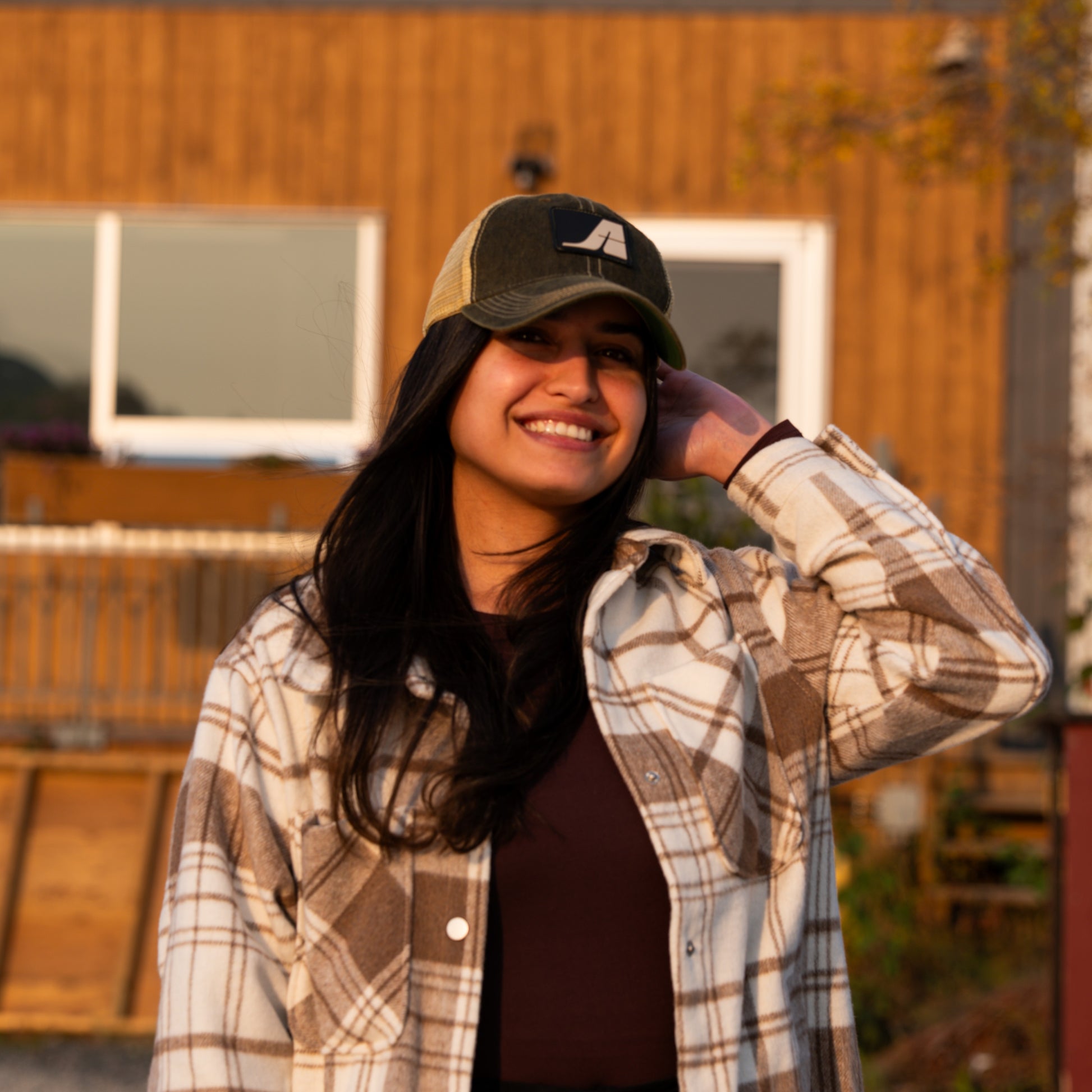 Model wearing a black and gold Air Tindi trucker hat